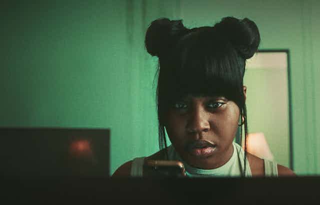 Exhausted young woman stares at her phone.