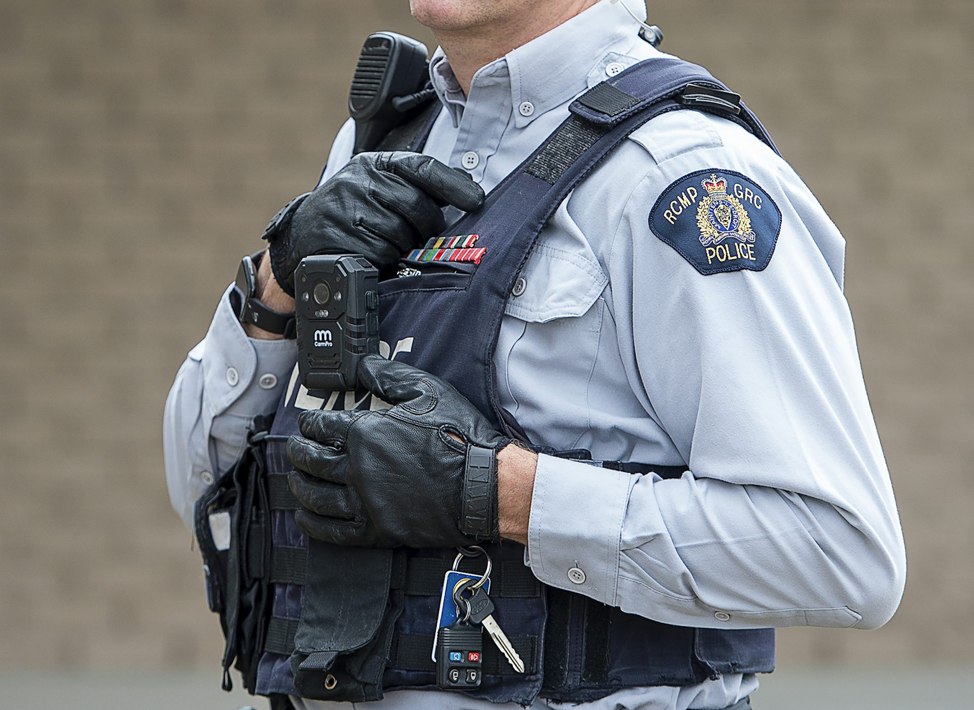 A police officer wearing a protective vest with RCMP written on their shirt sleeve.