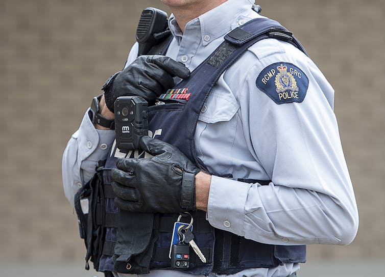 A police officer wearing a protective vest with RCMP written on their shirt sleeve.