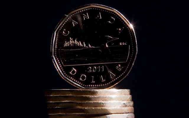 A one dollar Canadian coin balanced on a stack of other one dollar coins