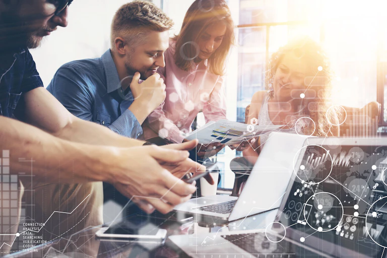 Empresarios jóvenes estudian datos en ordenadores y documentos.