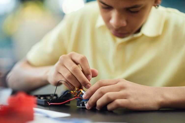 A student works with an electronic device.