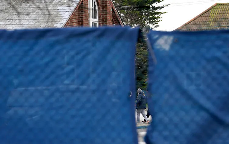 Glimpse of asylum seeker behind barrier in immigration centre.
