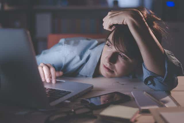 Mujer cansada y somnolienta trabajando en su ordenador portátil.