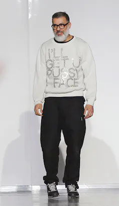 A bearded Ashish Gupta wears glasses and a sparkly white jumper.