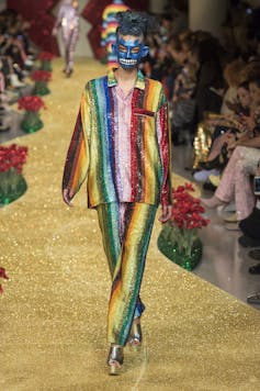 A model walks a yellow runway in rainbow striped, sequin pyjamas.