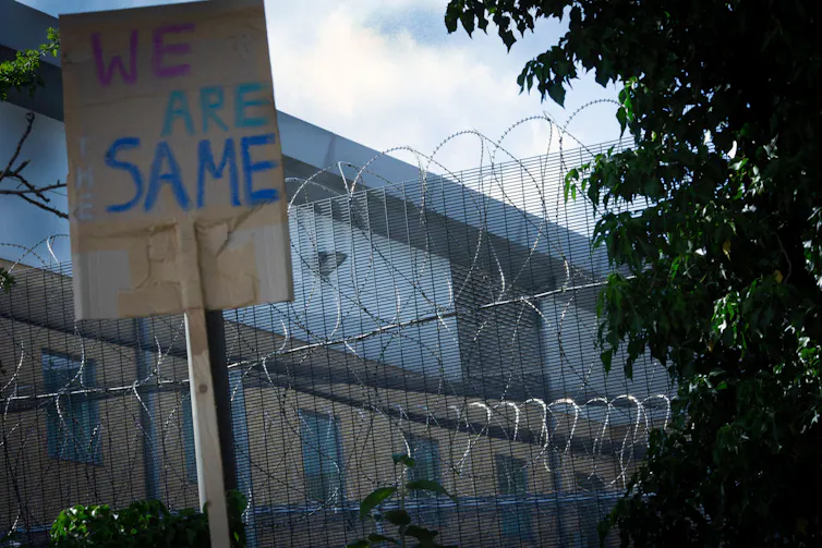 Placard in front of a razor wire fence