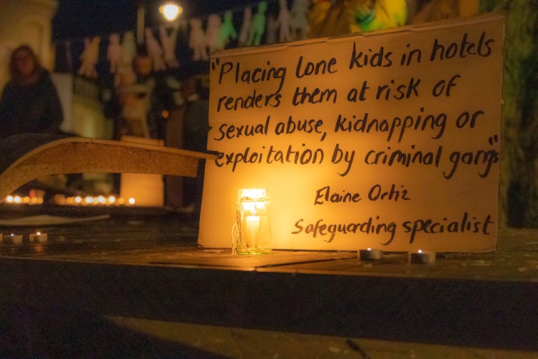 Placard lit by candle during night-time protest.