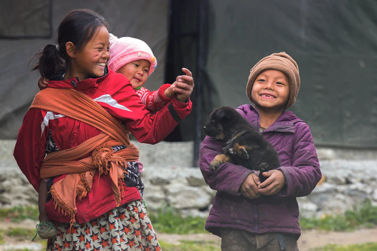 Three children with puppy, eldest daughter carrying baby on her back.