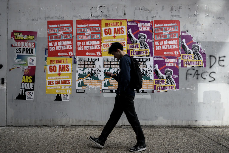 un étudiant marchant dans les couloirs d'une université où les murs sont couverts d'affiches appelant à la grève