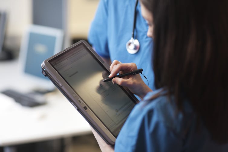 Close-up of health care provider accessing medical record on tablet