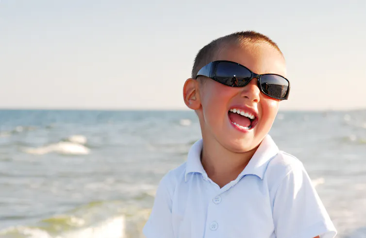enfant porte des lunettes de soleil à la plage