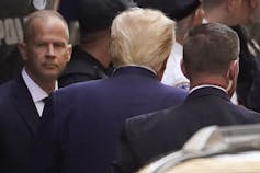 The back of a blond man's head is seen as he walks into a courthouse.