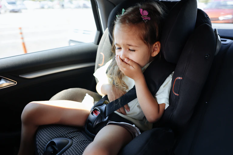 girl in carseat covers her mouth