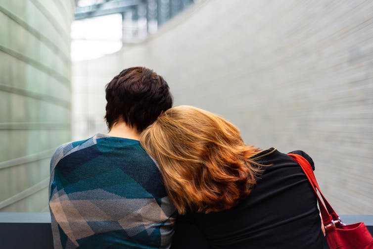 Woman places her head on a friend's shoulder