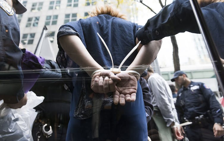 A climate activist is arrested during a protest in New York against BlackRock for investing in the fossil fuel industry, October 26, 2022.