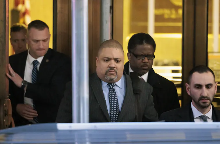New York district attorney, Alvin Bragg, walks out of a court building in Manhattan surrounded by aides.