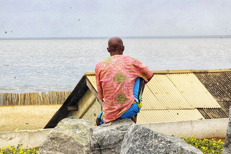 A man sitting on a rock looking at the ocean