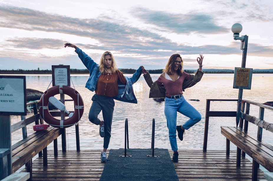 Two young women jumping beside a Finnish lake..