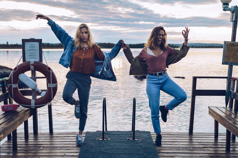 Two young women jumping beside a Finnish lake..