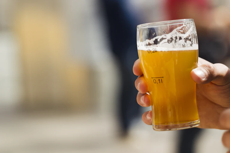 A hand holds up a glass of beer.