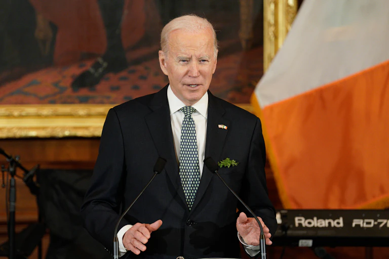 Joe Biden speaks at a podium in front of an Irish flag