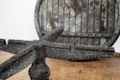 Metallic sculptures that look like machine parts are covered in spiky material.