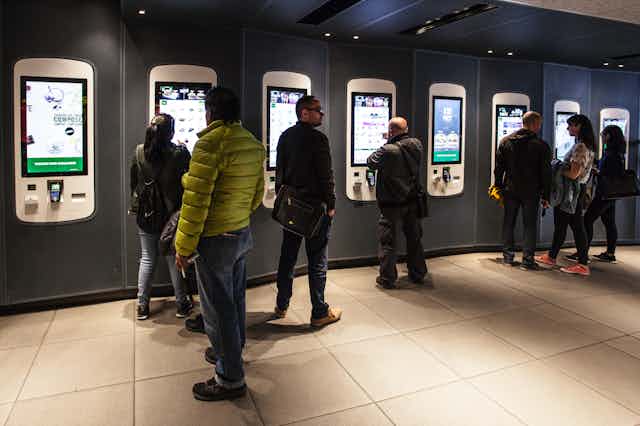 people queueing at self-service kiosks