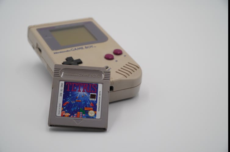 A grey square Tetris cartridge propped up against a Nintendo Game Boy console
