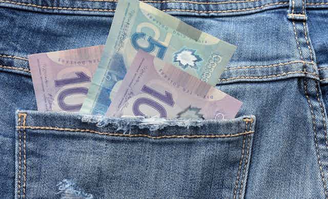 Canadian bills are seen in the pocket of a pair of jeans.