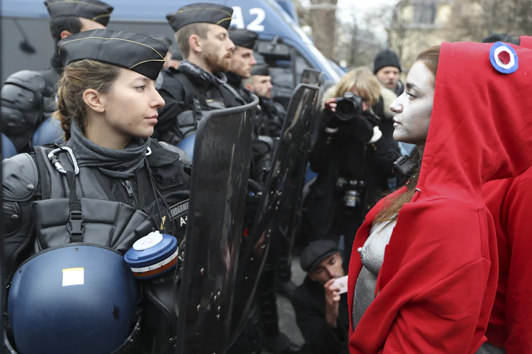 Femme gendarme faisant fasse à une manifestante habillée en "Marianne".