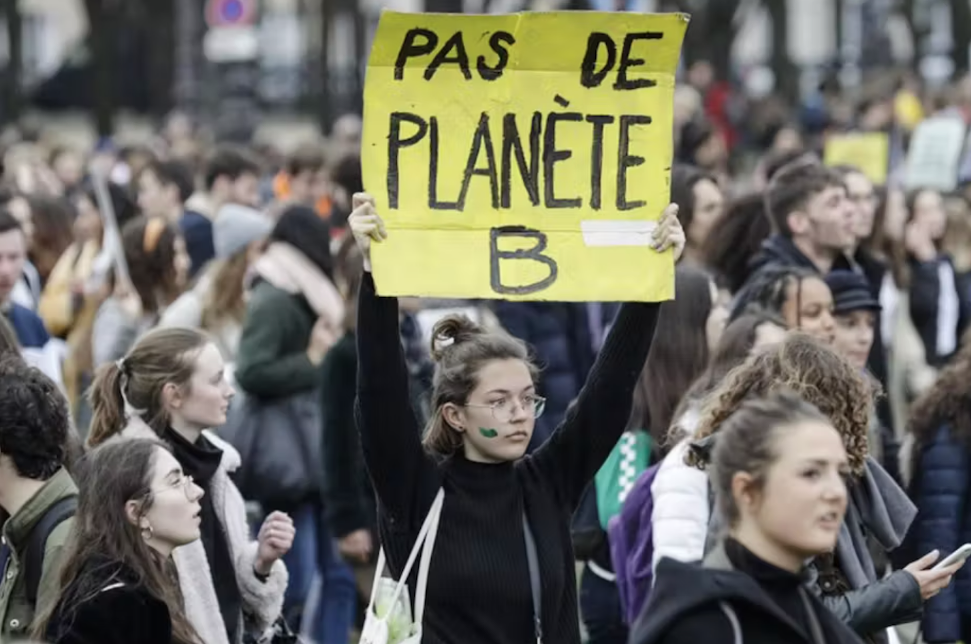 jeune femme qui brandit un panneau pas de planète b