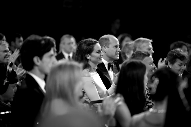 Prince Harry sitting in a crowd wearing a suit and tie.
