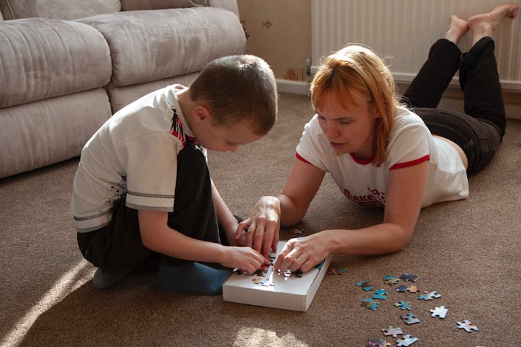 Adult and child do a crossword on the loungeroom floor