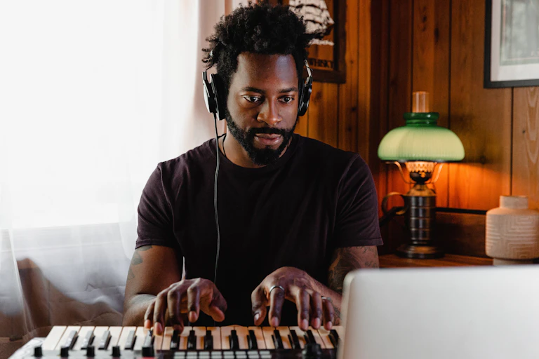 Man plays a keyboard while looking at a screen
