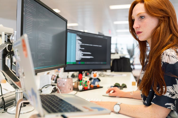 Woman works at a multi-screen computer