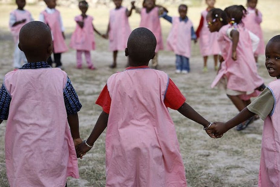 Des filles en uniforme rose se tenant par la main dans une cour