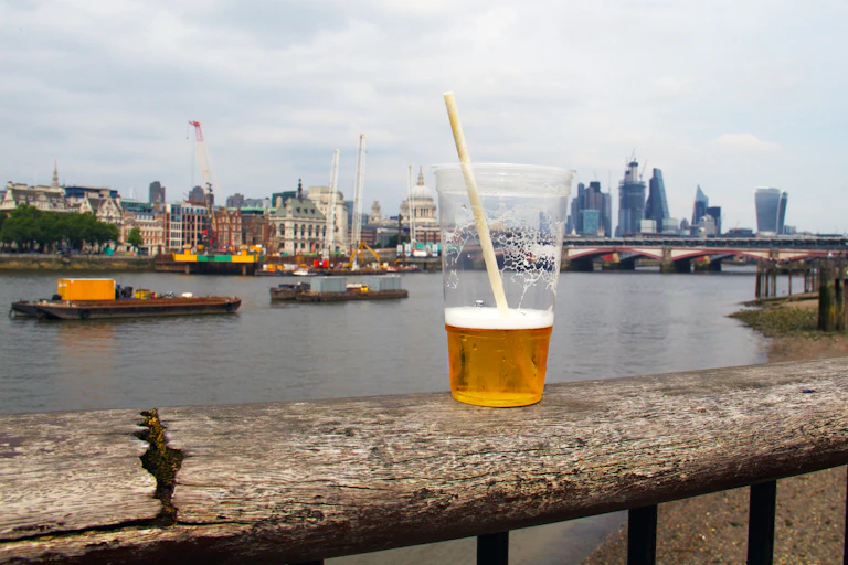 plastic cup of beer with london skyline in background