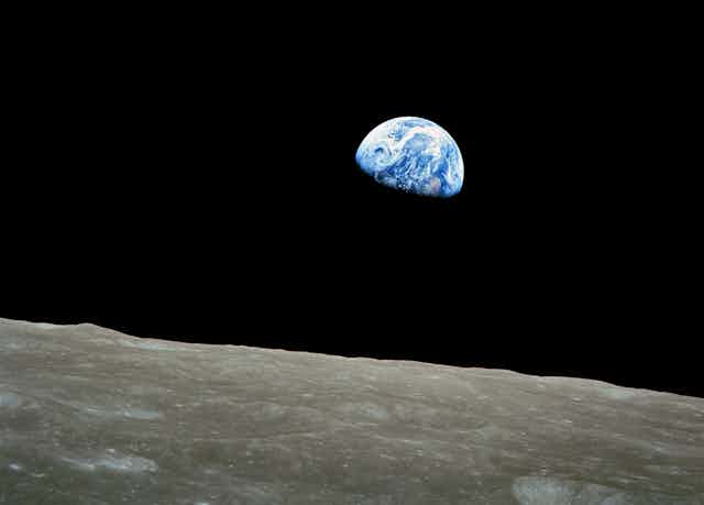 View of Earth taken from spacecraft with the Moon's surface in foreground.