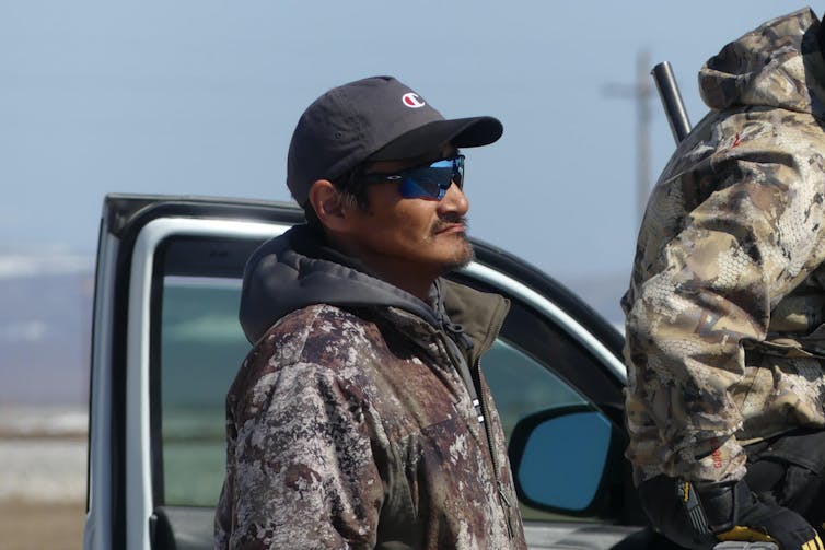 A profile image of Reppi swan, wearing a cap and camoflauge jacket