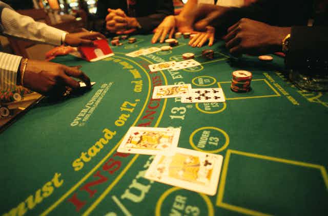 close-up of a blackjack table showing players' hands, pairs of cards face up and casino chips