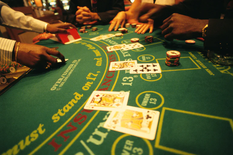 close-up of a blackjack table showing players' hands, pairs of cards face up and casino chips