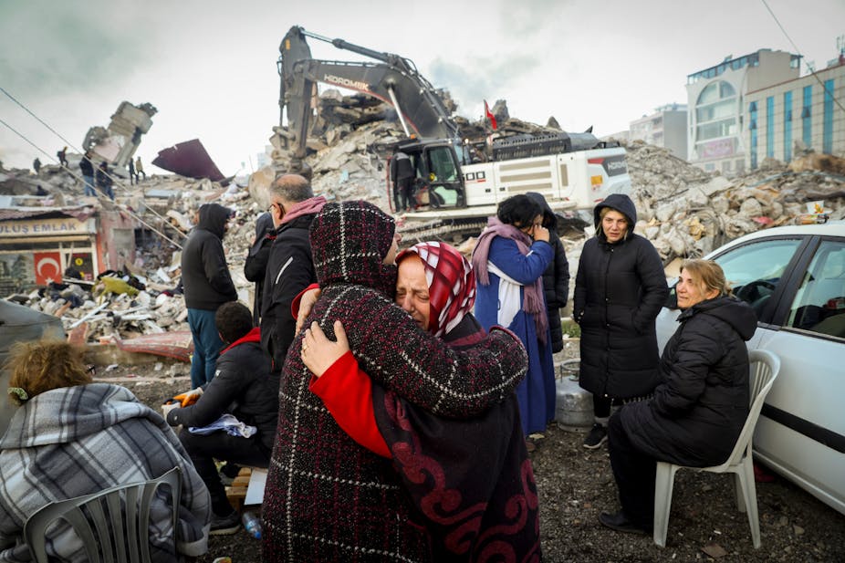 Personnes éplorées devant les ruines d'immeubles détruits par le séisme