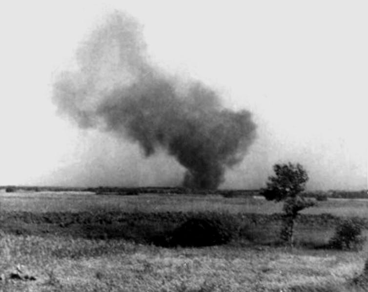A black and white photo shows a huge smoke cloud rising across a field.