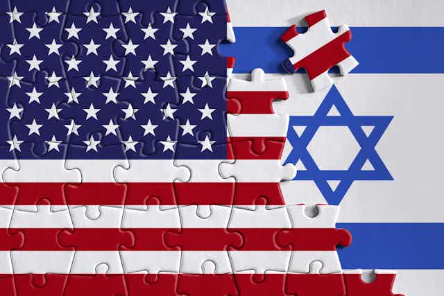 A puzzle piece of the United States flag is placed over a blue and white stripped flag with a Jewish star.