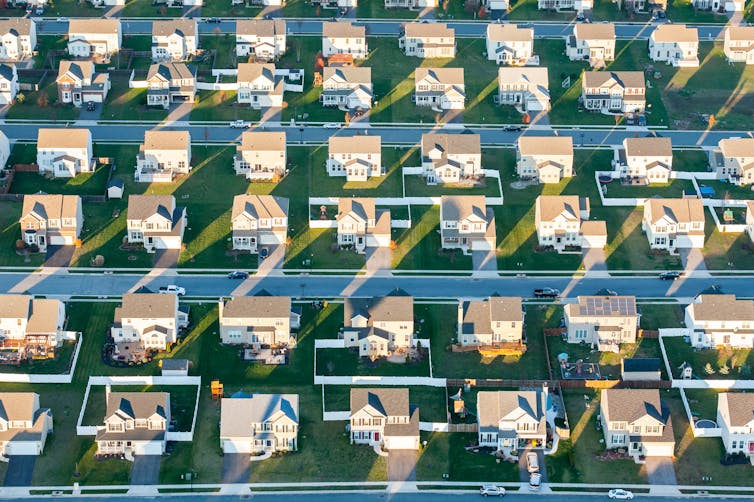 A bird's eye view of suburban houses with green lawns.
