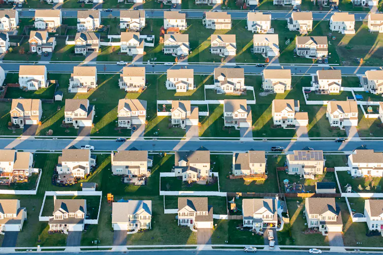 A bird's eye view of suburban houses with green lawns.