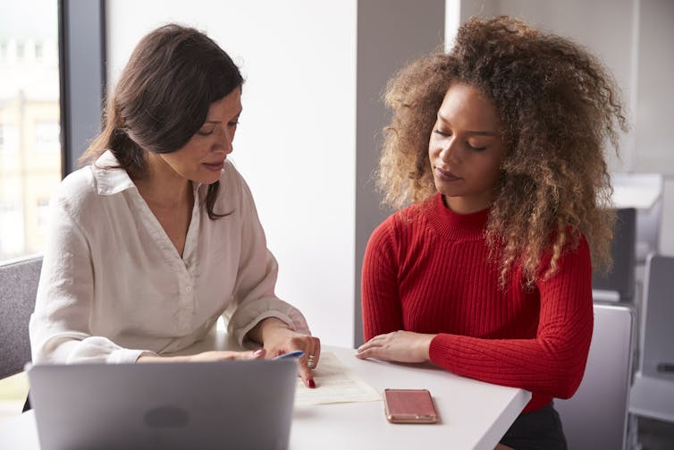 Two women sitting at a desk and having a discussion