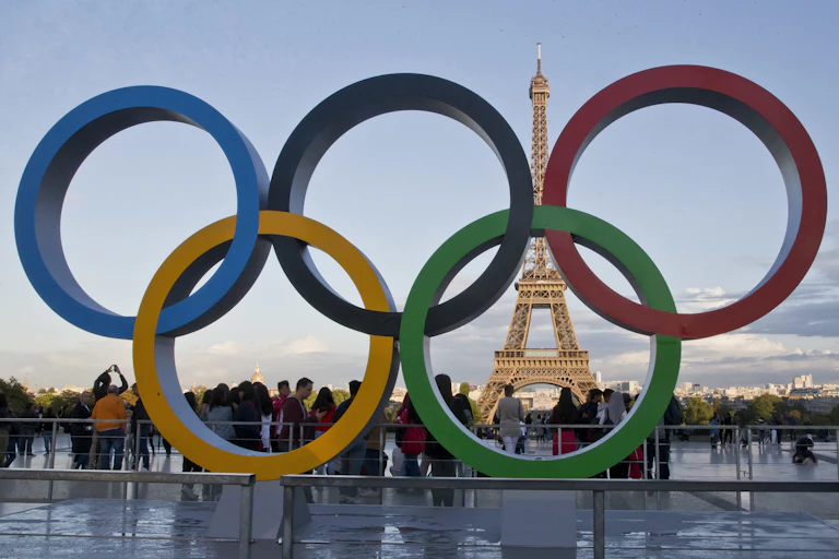The Eifel Tower is seen through a sculpture of five overlapping rings in the colours blue, yellow, black, green and red