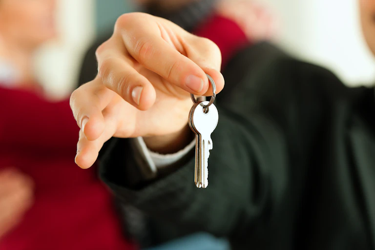 Man in a suit holding out keys.